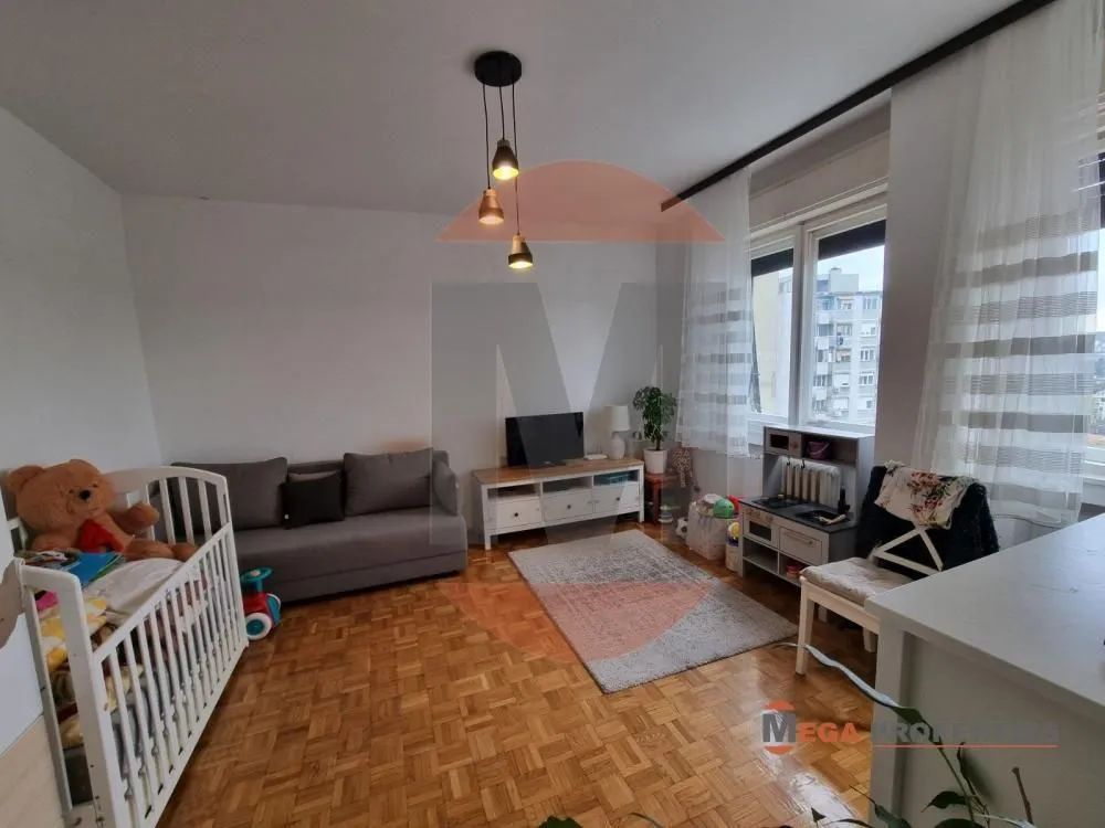 Living room with a sofa, TV, and a baby crib.