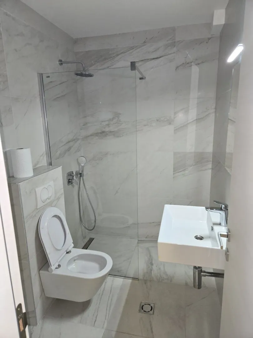 Modern bathroom with a shower cabin and white tiles.