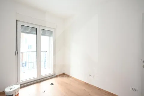 Prazna soba sa bijelim zidovima, drvenim podom i balkonskim vratima. - image 12