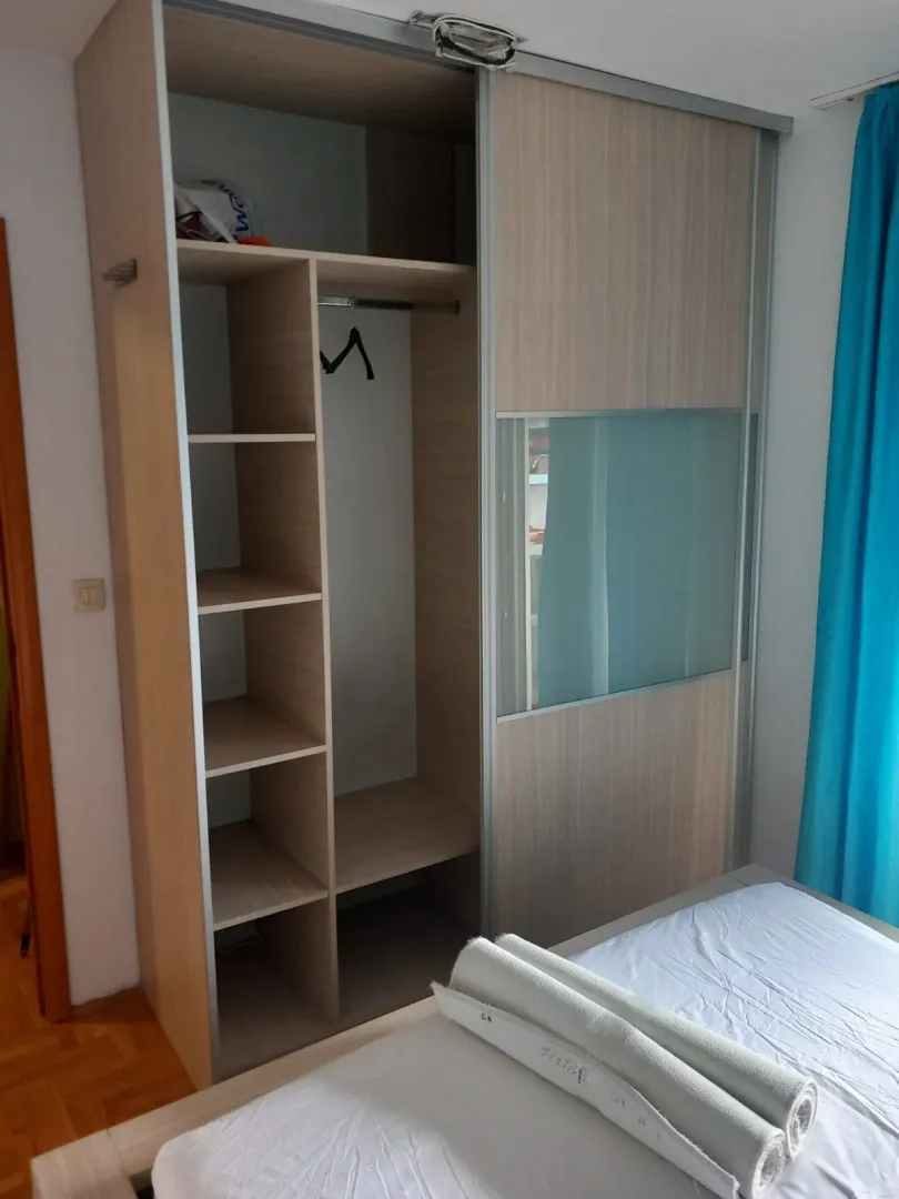 Spavaća soba sa velikim ugradnim plakarem pored kreveta.