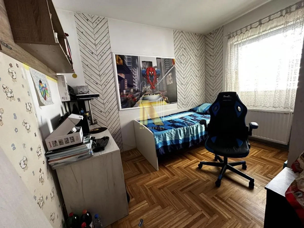 Dečja soba sa krevetom, radnim stolom i stolicom.