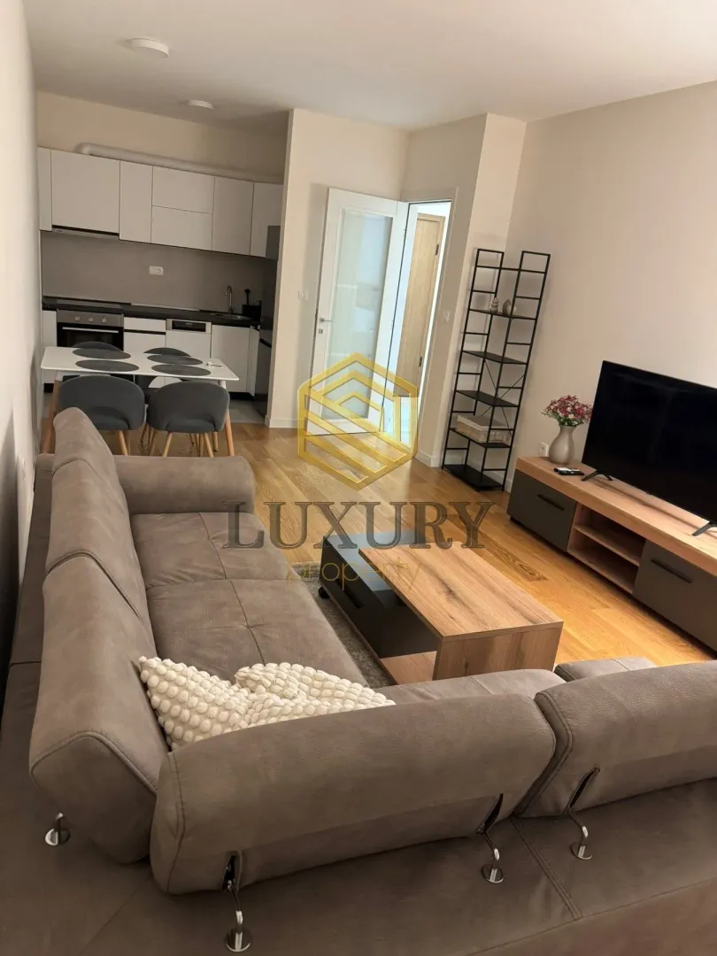 Living room with a sofa, TV, and an adjoining dining area.