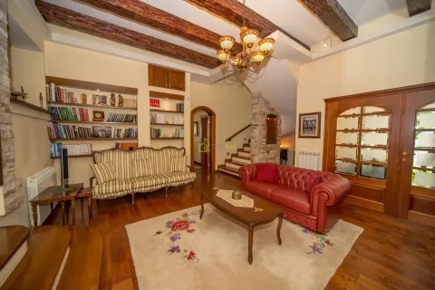 Spacious living room with wooden ceiling beams, seating furniture, and bookshelves. - image 44