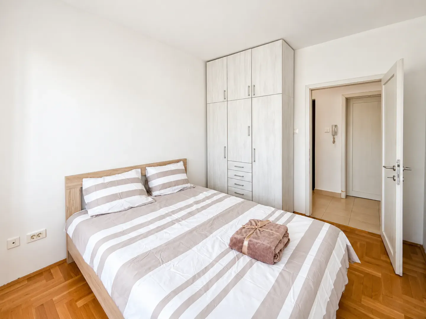 Furnished bedroom with a double bed, wardrobe, and wooden flooring.