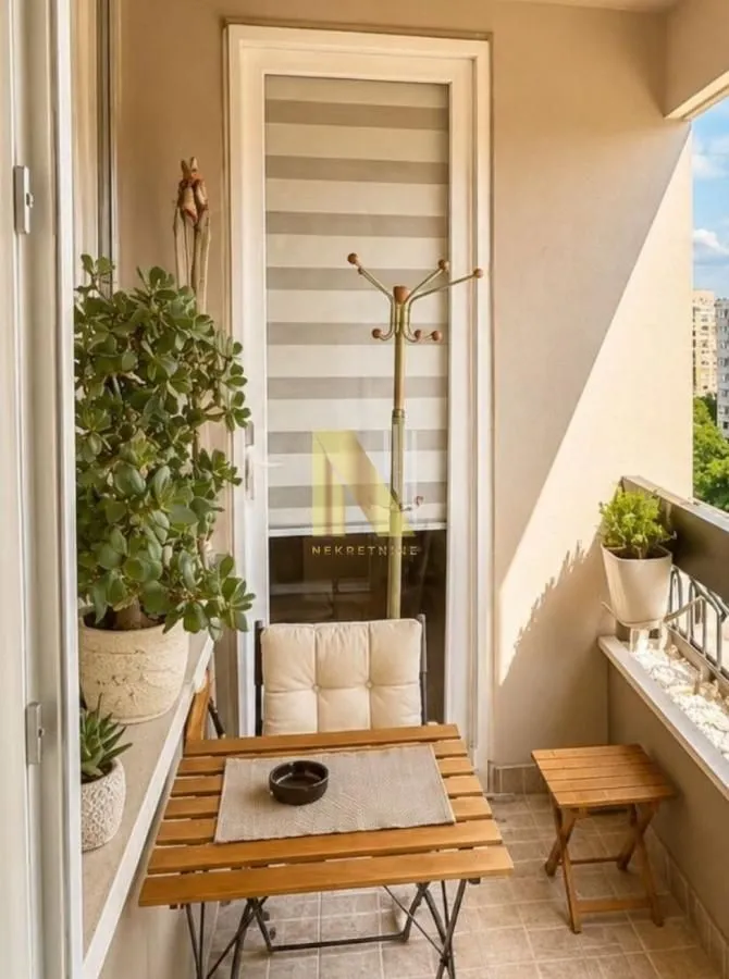 Manji namešteni balkon sa stolom, stolicom i sobnim biljkama.
