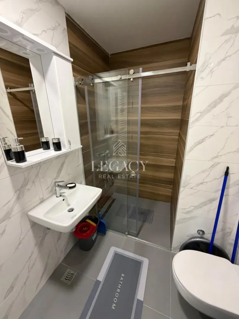 Modern bathroom with a walk-in shower, washbasin, and mirror.