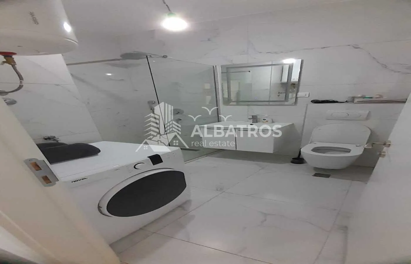 Modernly equipped bathroom with a walk-in shower, washbasin, toilet, and washing machine.