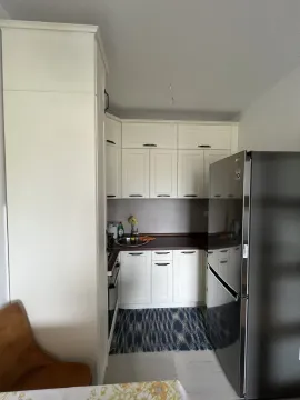 Bright kitchen with white cabinets and a modern refrigerator. - image 7