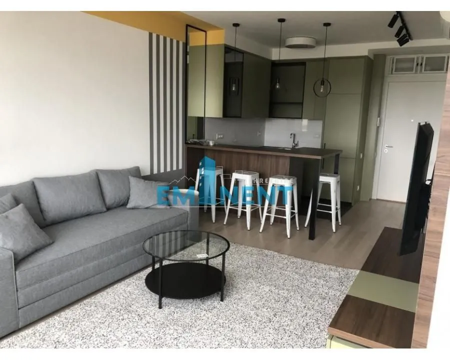 Living room with a sofa and a view of the kitchen with a bar counter.
