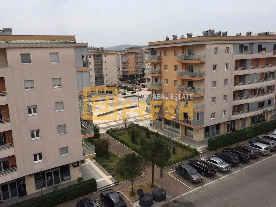 Pogled sa prozora na okolne zgrade, trg i parking.