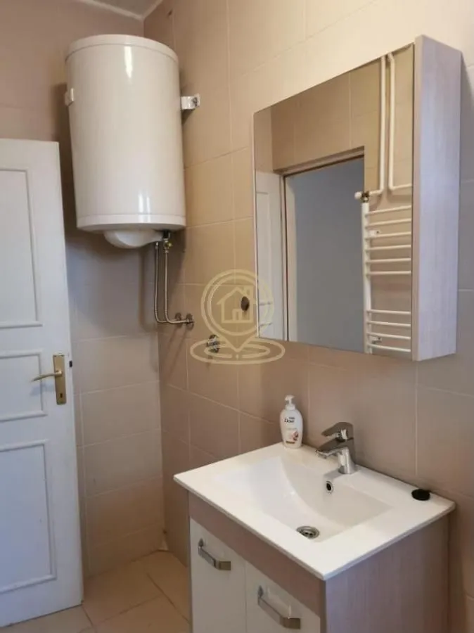 Smaller bathroom with a sink, mirror and a water heater on the wall.