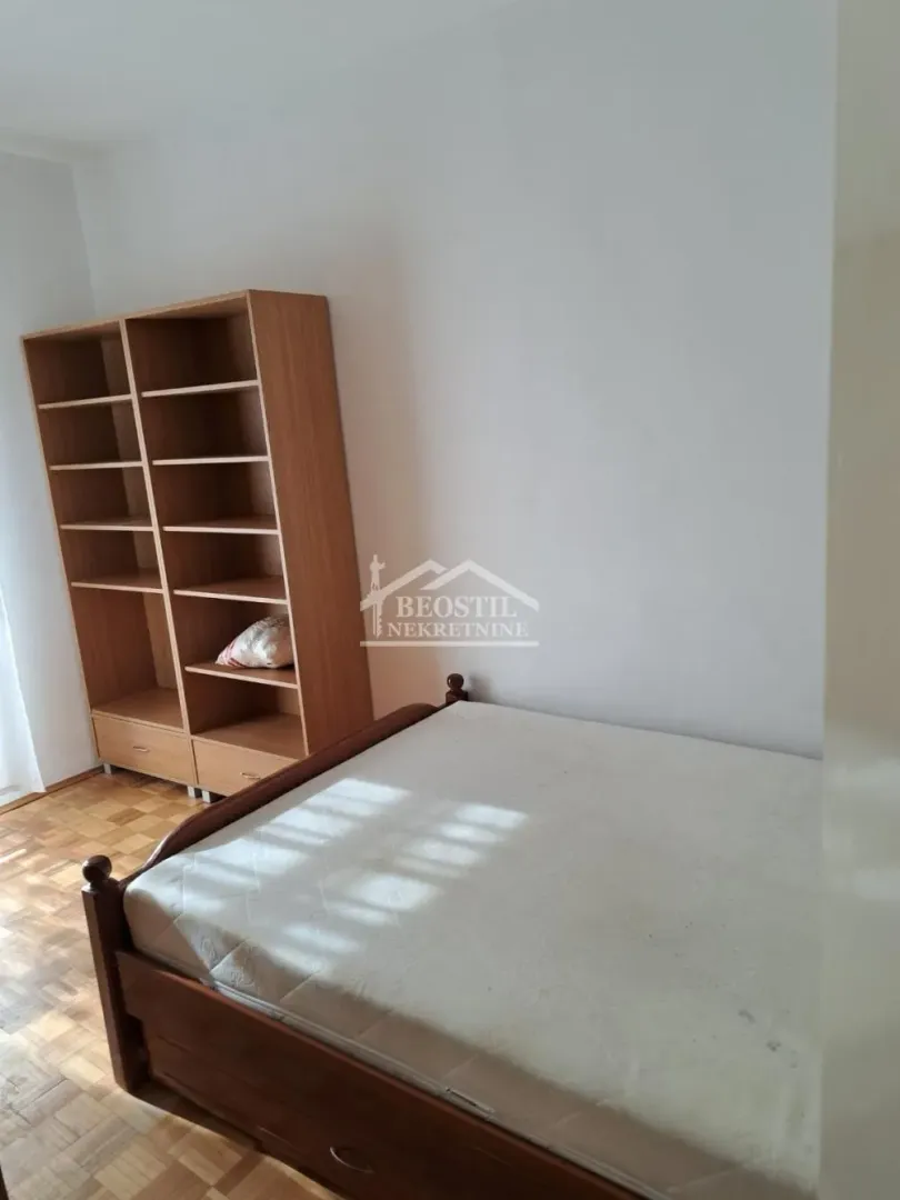 Bedroom with a bed and a wooden bookshelf.