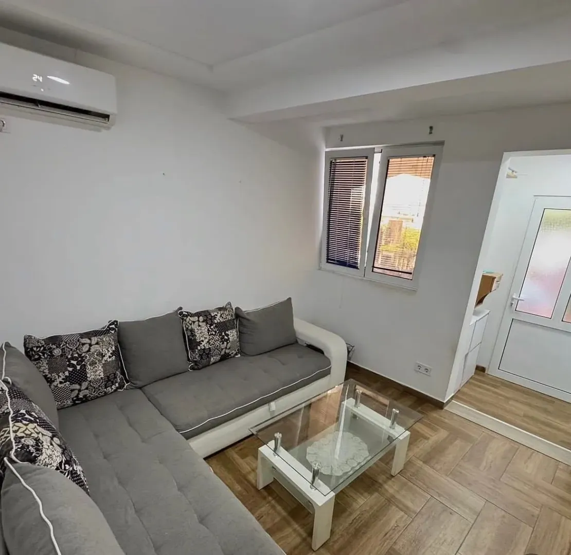 Living room with a sectional sofa, coffee table, and air conditioning unit.