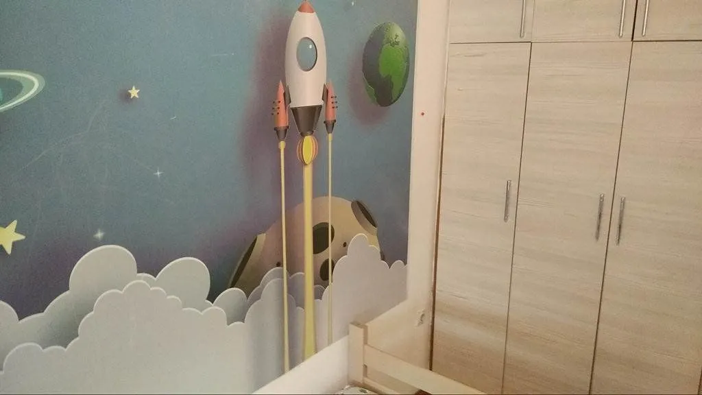 Dječja spavaća soba sa tapetom sa motivom svemira i ugradnim ormarom.