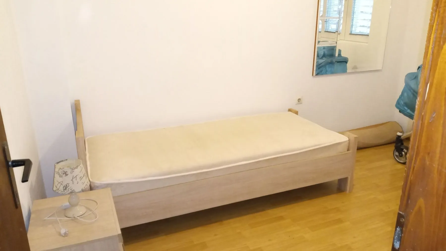 A simple bedroom featuring a single bed and a nightstand.