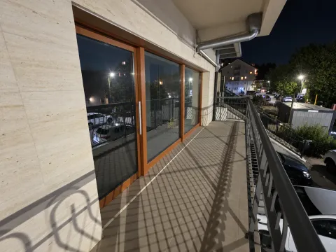 Spacious covered balcony with a metal railing and a view of the street at night. - image 5