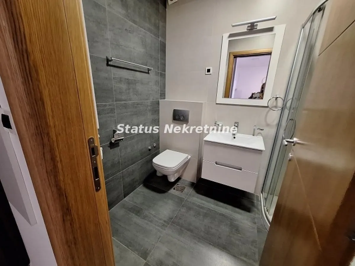 Moderno opremljeno kupatilo sa tuš kabinom i sivim keramičkim pločicama.