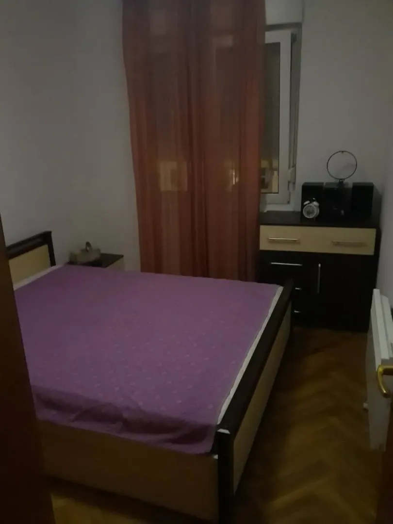 Manja spavaća soba sa bračnim krevetom i prozorom.