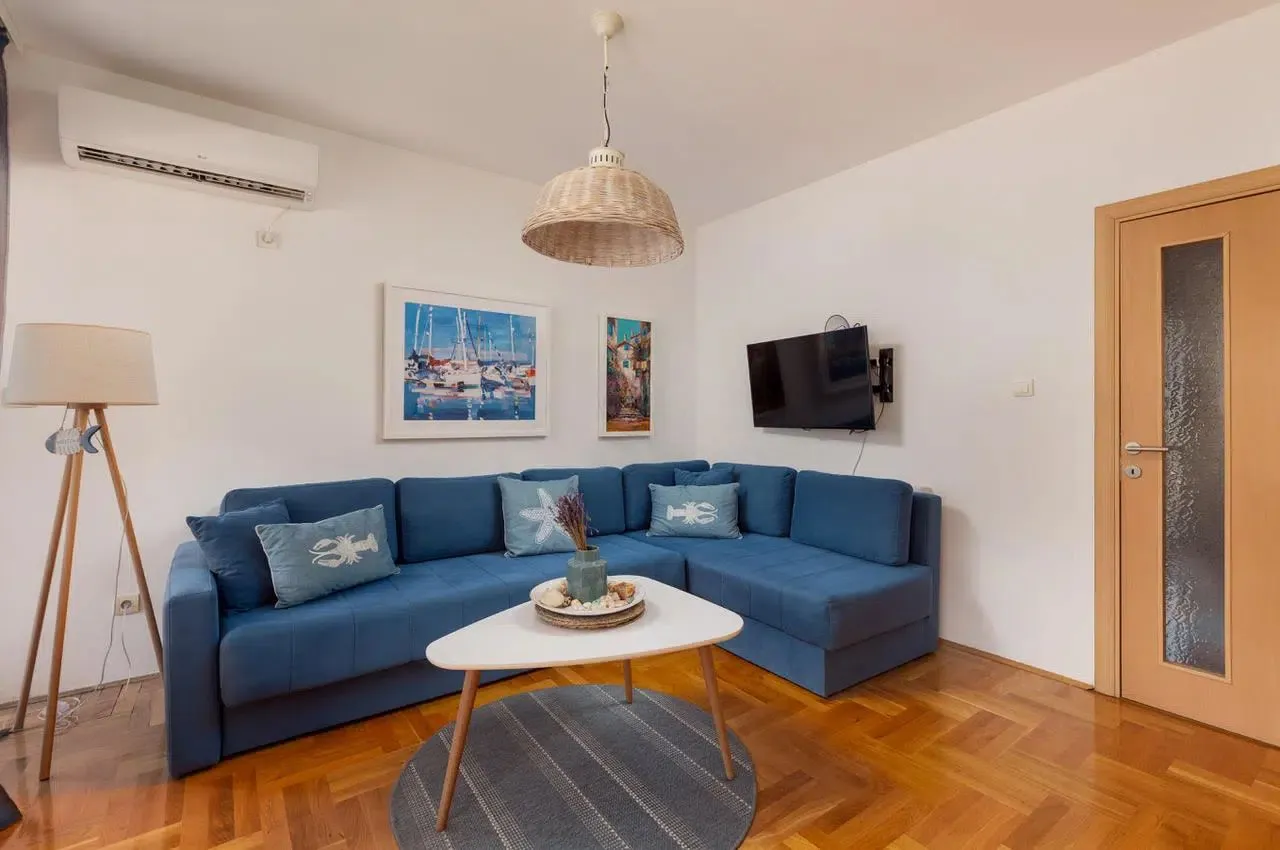 Living room with a blue sectional sofa and wooden floor.