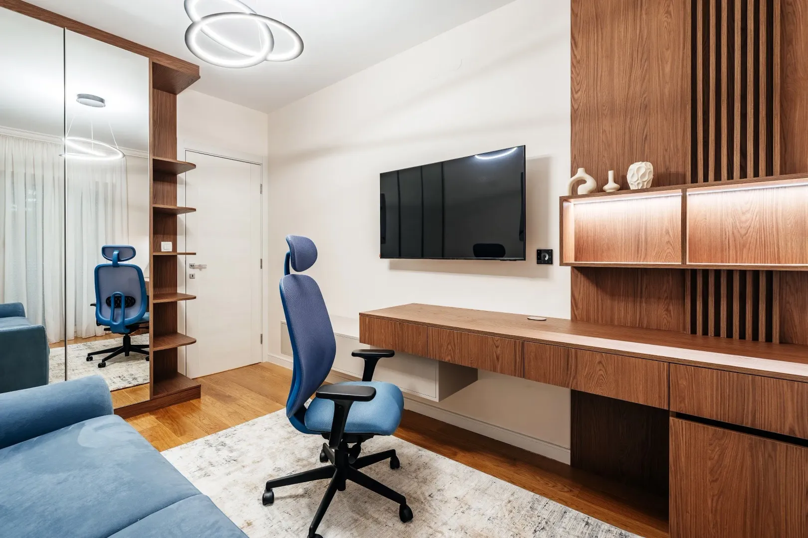 Living room with a desk, blue office chair, and a wall-mounted TV.