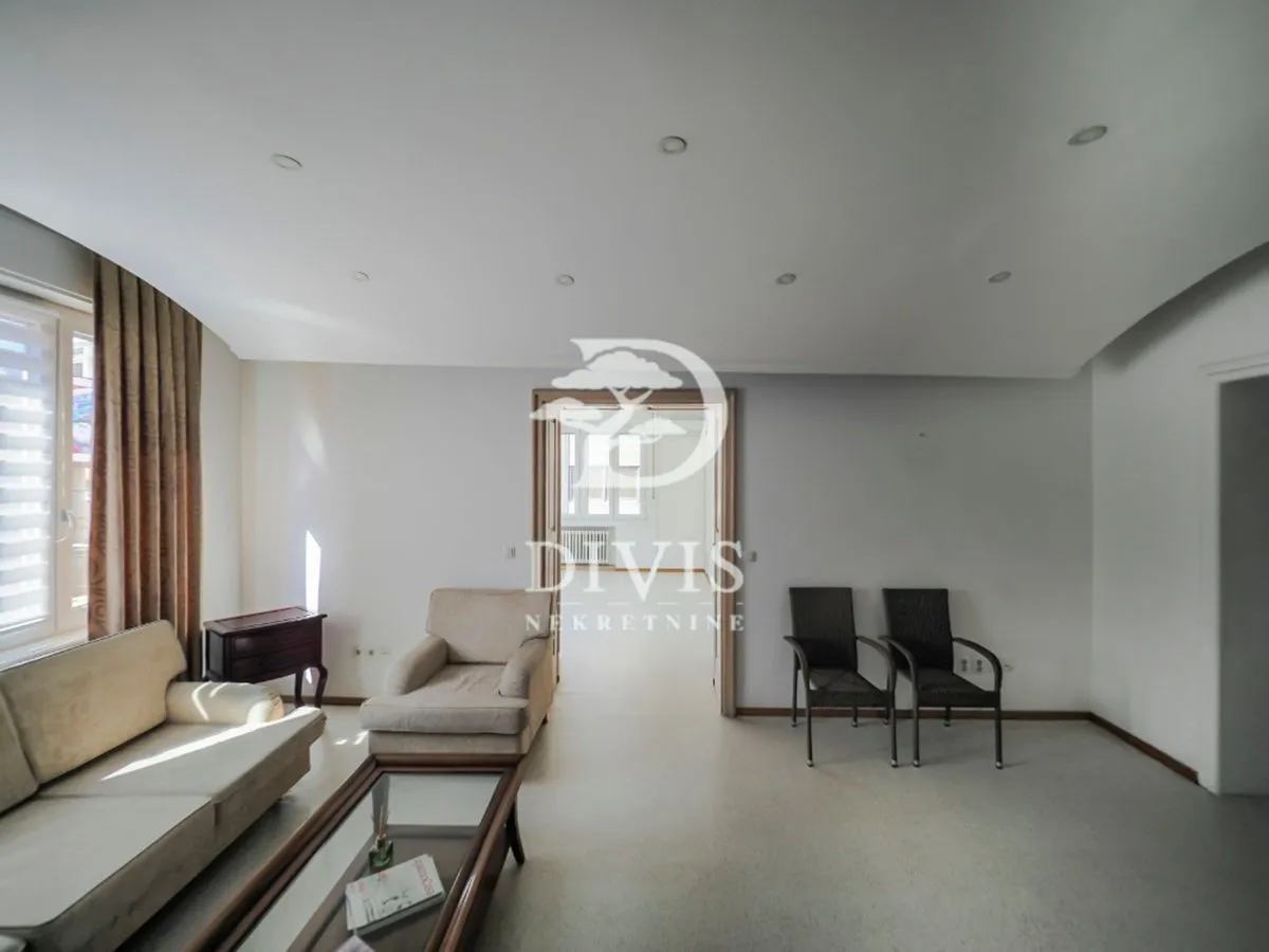 Spacious living room with a sofa set, armchair, and a view into the adjacent room.