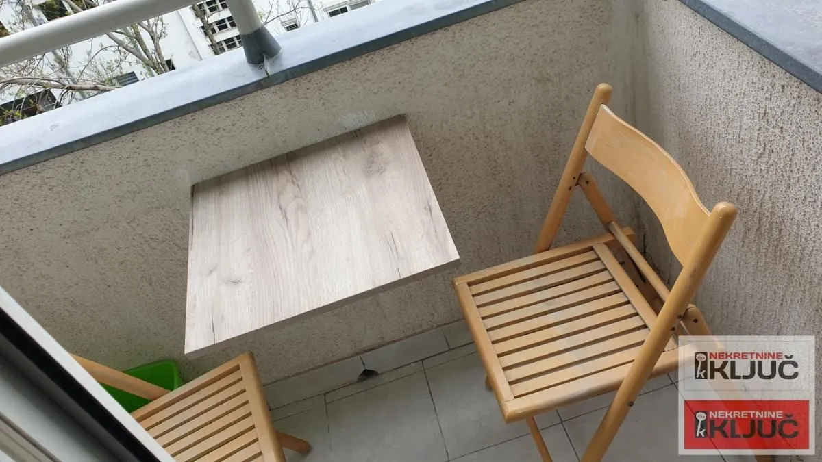 Manji balkon sa drvenim stolom i stolicama.