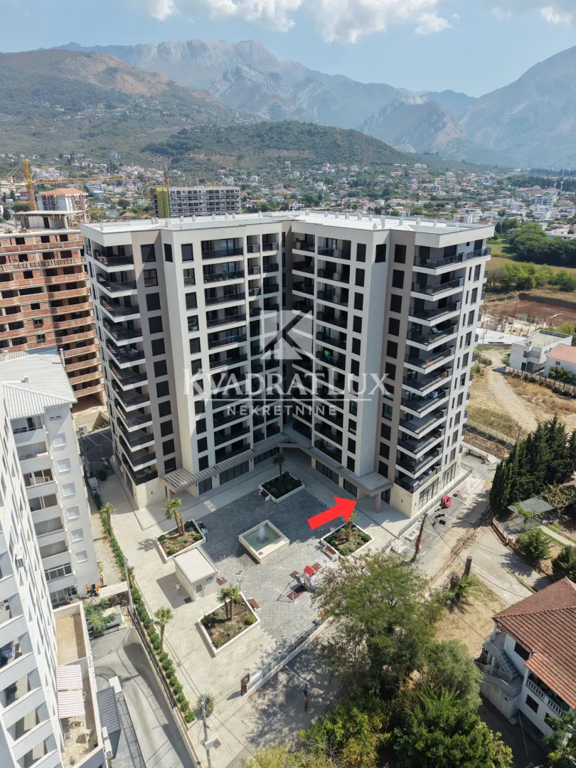 Aerial view of a new residential building with a landscaped courtyard and mountains in the background.