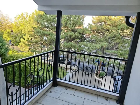 Natkriveni balkon sa crnom ogradom i pogledom na zelenilo i dvorište. - image 13