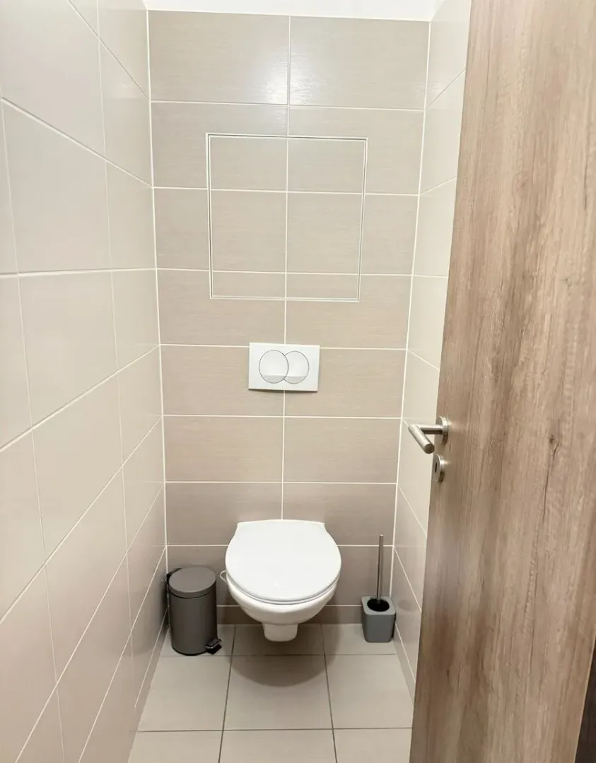 Manje kupatilo sa WC šoljom i svijetlim pločicama.