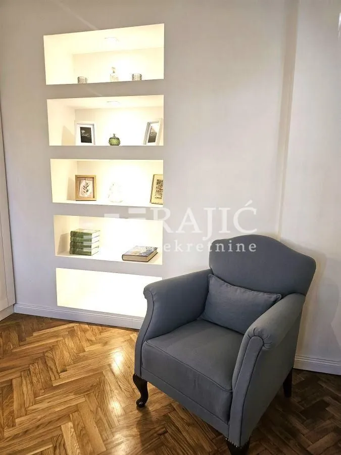 A comfortable armchair next to a wall with built-in niches and shelving.