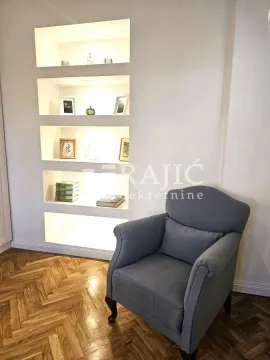 A comfortable armchair next to a wall with built-in niches and shelving. - image 13