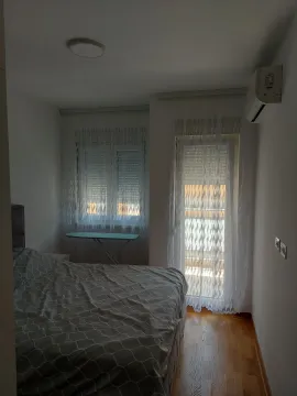 Spavaća soba sa bračnim krevetom, klima uređajem i prozorom sa zavjesama. - image 7