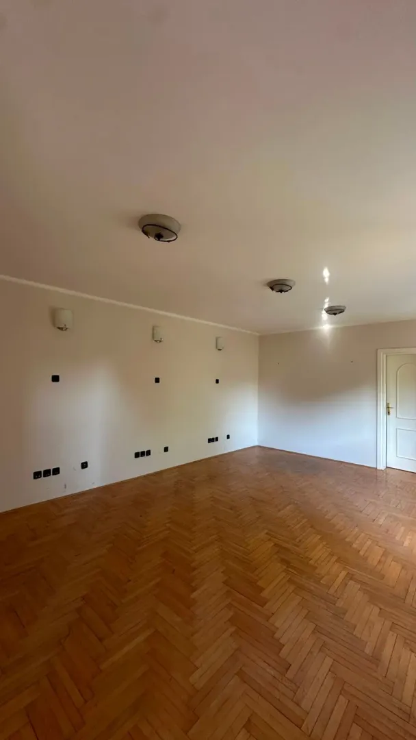 Empty room with wooden parquet flooring and white walls.