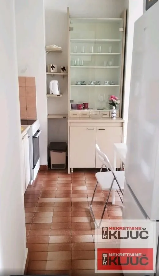 Manja kuhinja sa trpezarijskim stolom i kuhinjskim elementima.