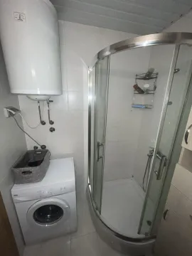 A bathroom featuring a shower cabin, washing machine, and water heater. - image 4