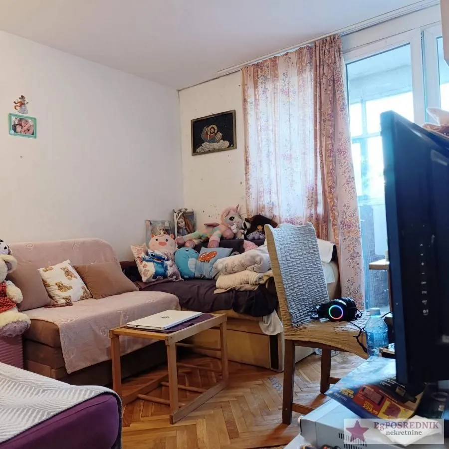Nameštena dnevna soba sa garniturom i prozorom.