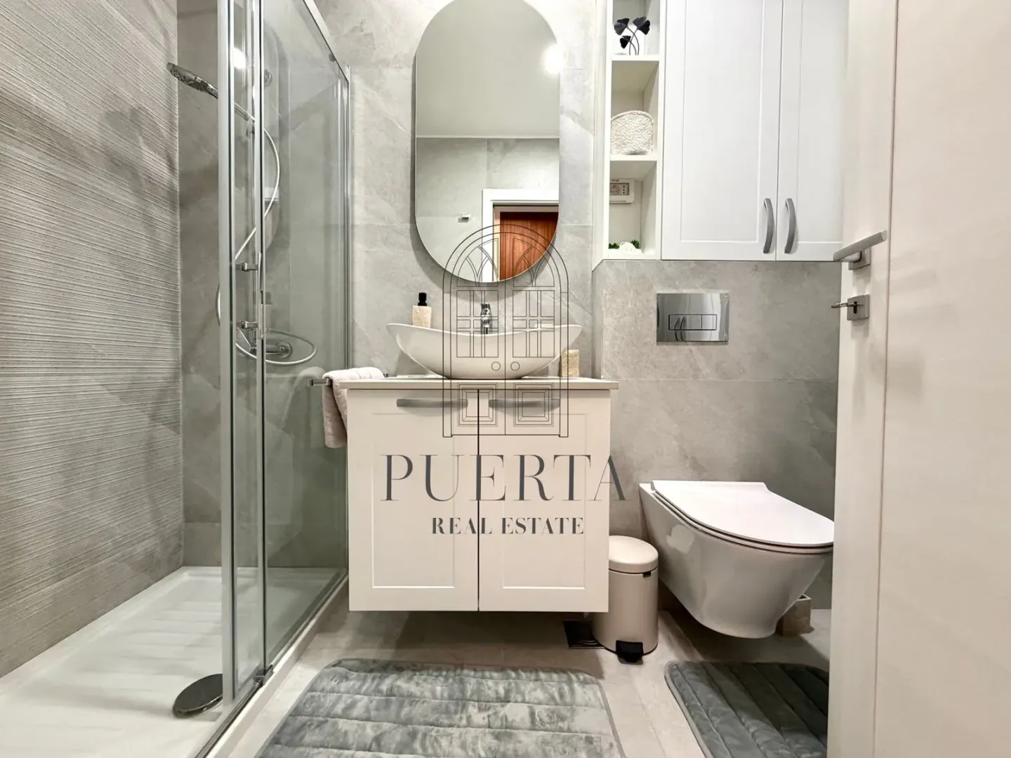 Modernly decorated bathroom with a walk-in shower, washbasin, and wall-mounted toilet.