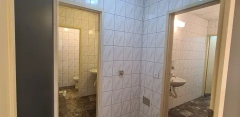 A view of a tiled bathroom with a washbasin and a doorway leading to a toilet. - image 5
