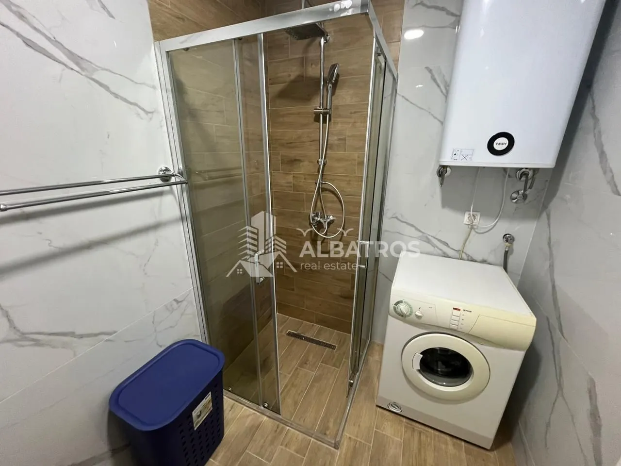 Modern bathroom with a shower cabin, water heater, and washing machine.