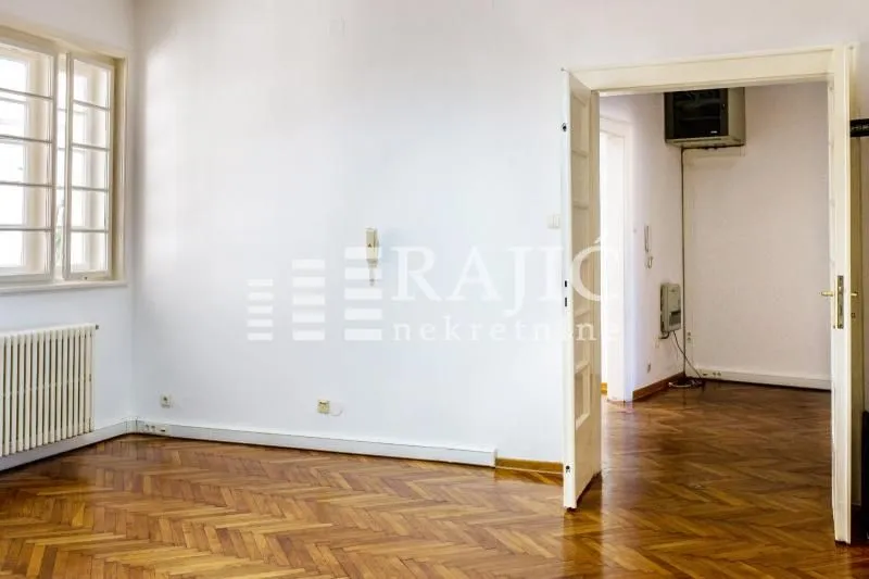 Empty room with parquet flooring and a window.