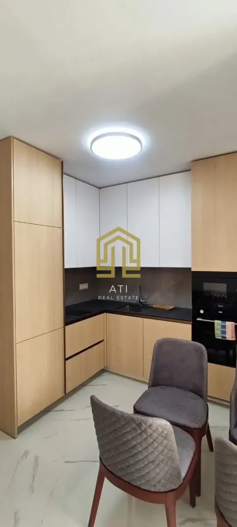 Moderna kuhinja sa drvenim elementima i ugrađenim aparatima.