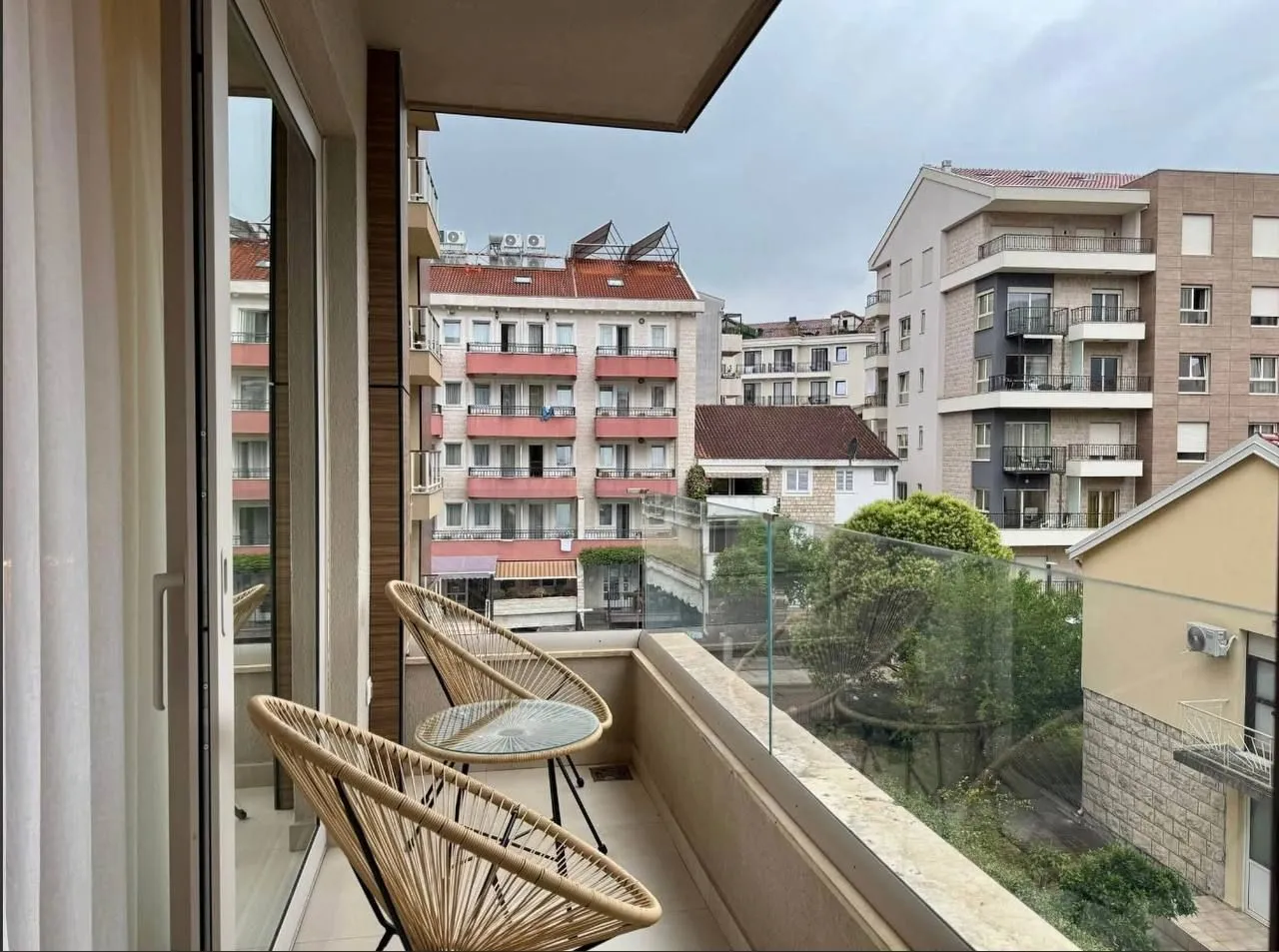 Namješten balkon sa garniturom za sjedenje i pogledom na gradsko naselje.