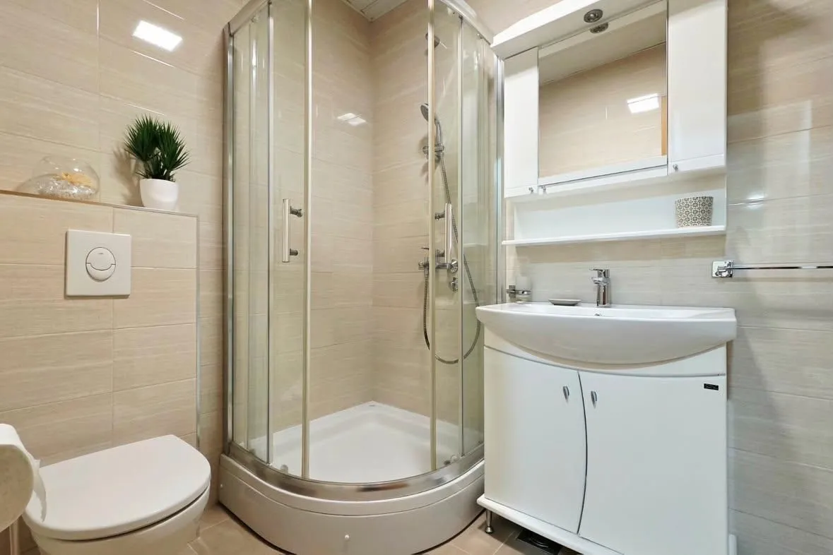 Furnished bathroom with a shower cabin, sink, and toilet.