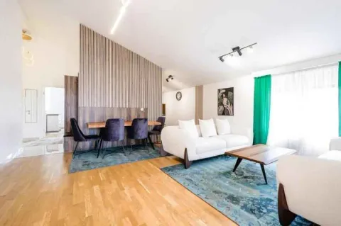 Prostrana dnevna soba sa garniturom, trpezarijskim stolom i modernim drvenim panelima. - image 3