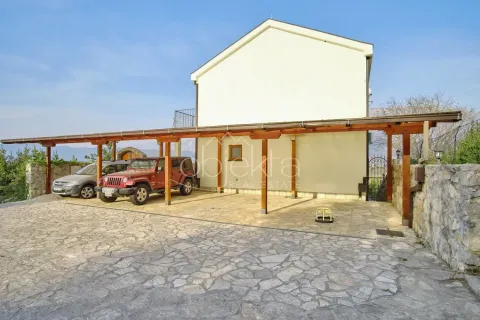 Pogled na spoljašnjost kuće sa nadstrešnicom za automobile i dvorištem popločanim kamenom. - image 4
