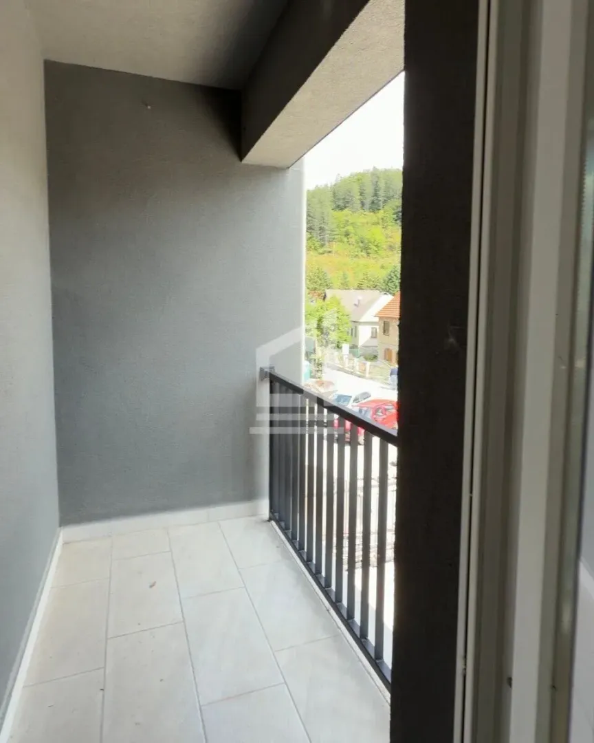 Natkriveni balkon sa pločicama i pogledom na okolinu.