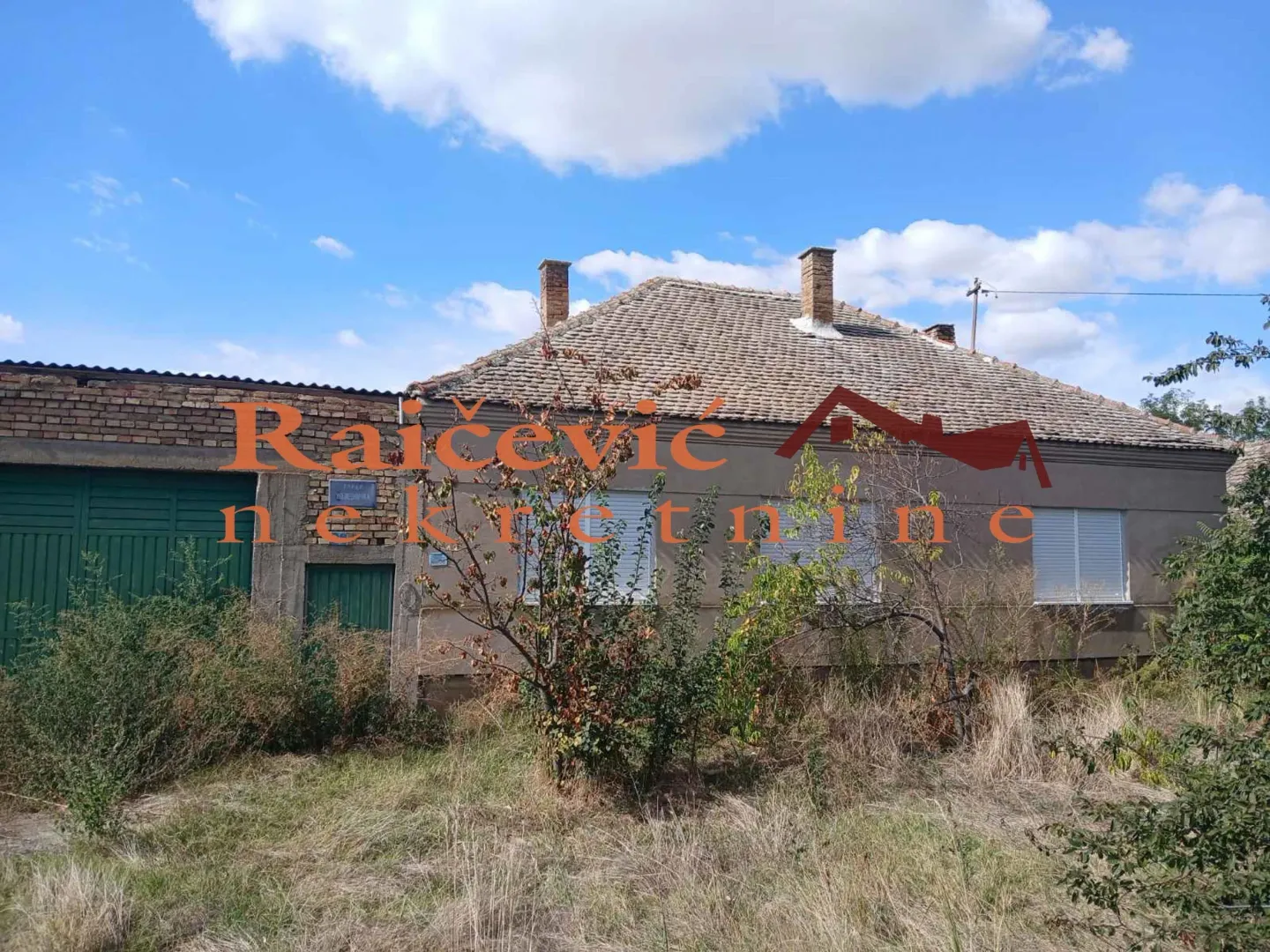 Pogled na spoljašnjost starije prizemne kuće sa dvorištem.