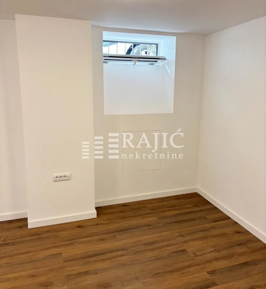 Empty room with white walls and wooden flooring.