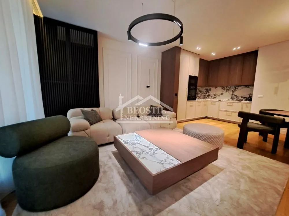 Living room with sofa set and view of the kitchen in the background.