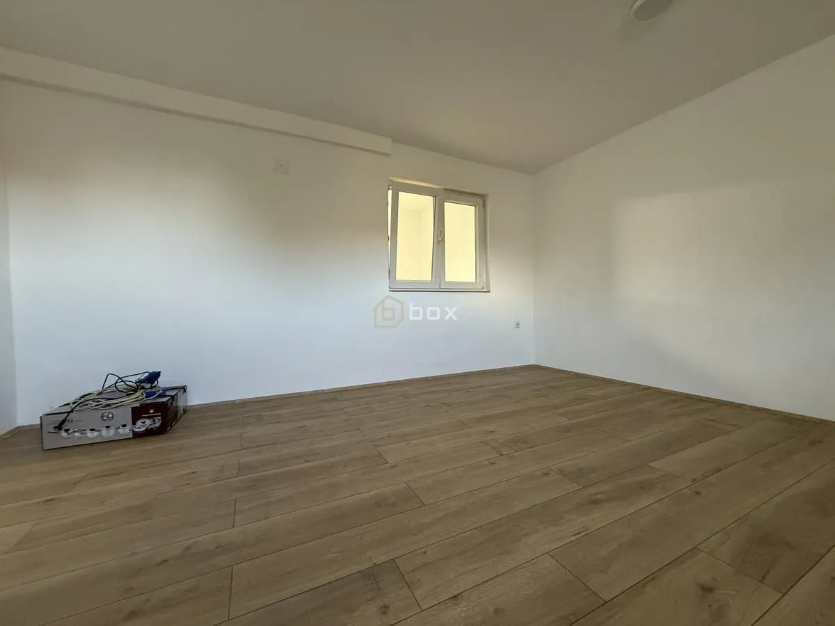 Empty room with white walls and wooden flooring.